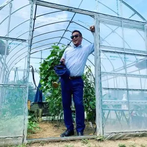 ビニールハウスの入り口に立つしーたけ村長